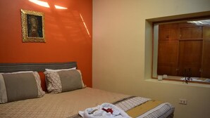 A hotel room with a bed, pillows, a framed picture on the wall, and a window with a view of a wooden structure. - Casa Riso Cusco I (Cusco)