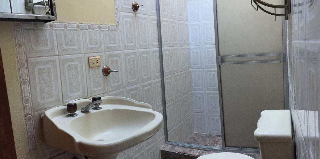 A bathroom with a sink, toilet, and shower area.