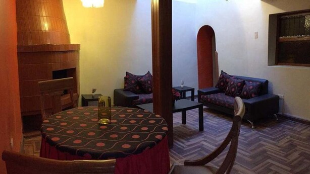 A cozy living area with a round table, two sofas, a small table, and a fireplace. - Casa Riso Cusco I (Cusco)