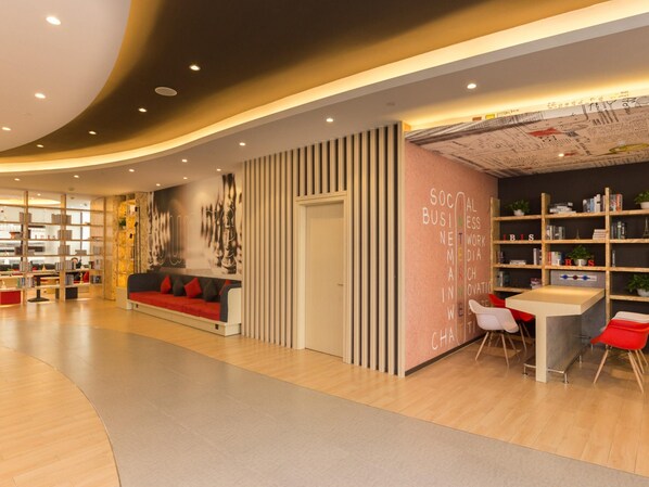 A modern interior with a curved ceiling, a red sofa, bookshelves, and a wall with text. - ibis Shenyang north station (Shenyang)