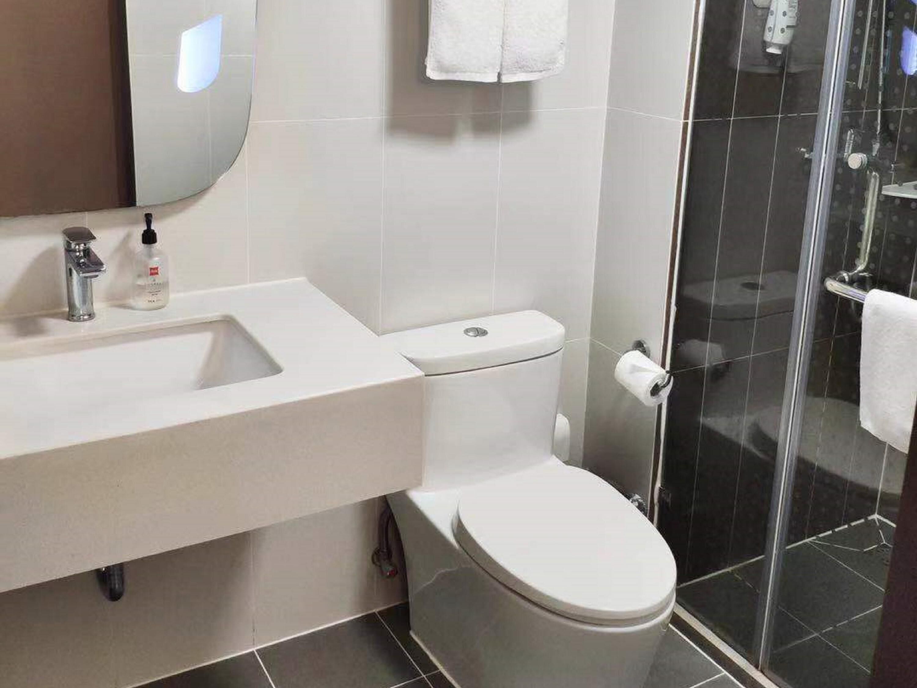 Un baño moderno con lavamanos, inodoro y ducha blancos.