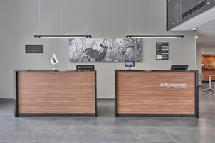 Una recepción con una obra de arte de la ciudad, una pantalla digital y un letrero de CityExpress Hotels.