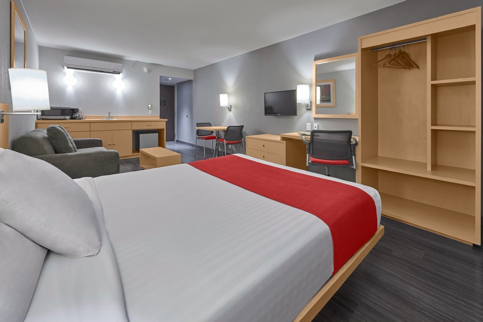 Une chambre d’hôtel équipée d’un lit, d’un bureau, d’une chaise, d’une armoire et d’un téléviseur.