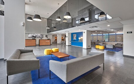 A spacious lobby with a high ceiling, modern furniture, and a view of the outdoors.