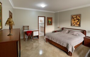 Un dormitorio con cama, escritorio, silla y mesita de noche.