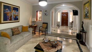 A living room with a sofa, a coffee table, and a chandelier. There is a door leading to another room. - Cesar's House Guayaquil (Guayaquil)