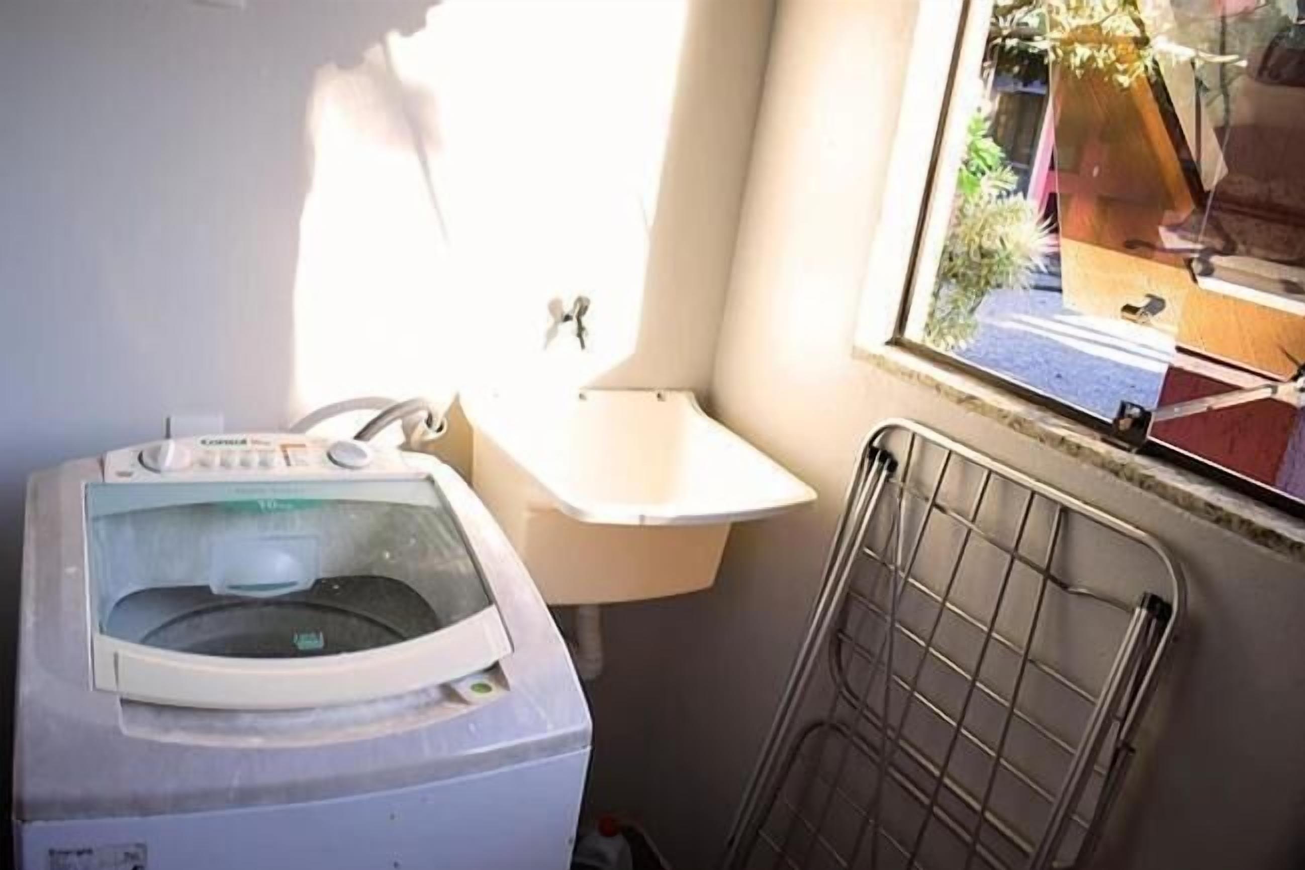 Un área de lavandería compacta con lavadora, lavamanos pequeño y radiador.