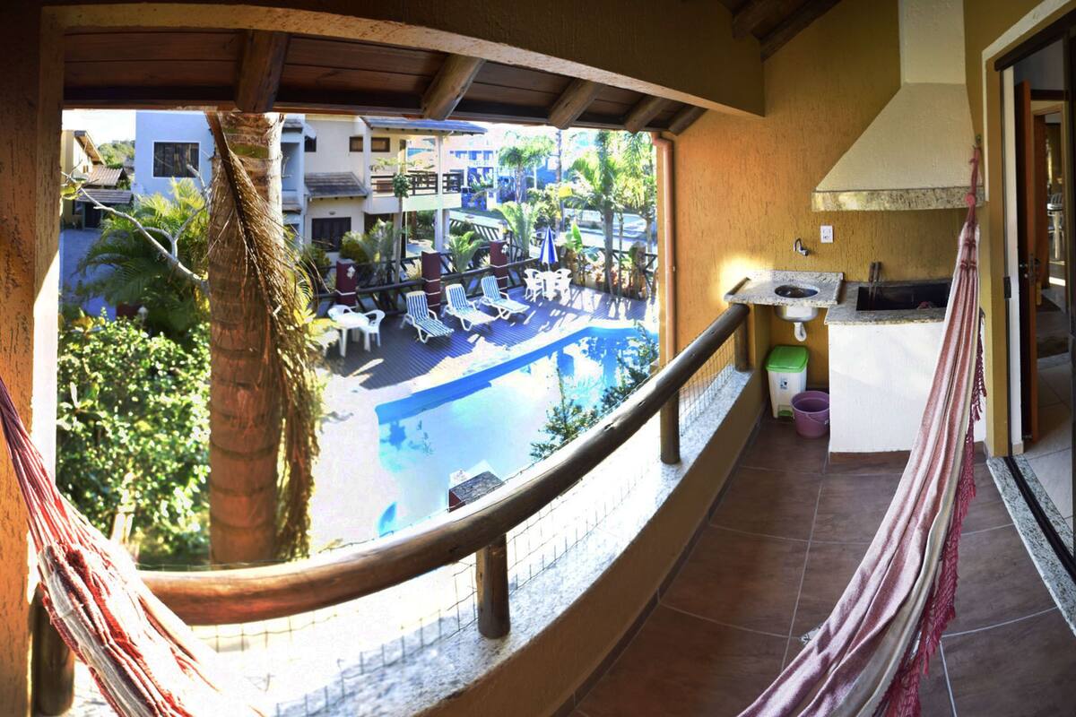 Ein Balkon mit Blick auf ein Schwimmbecken, Liegestühle und eine kleine Küchenzeile.