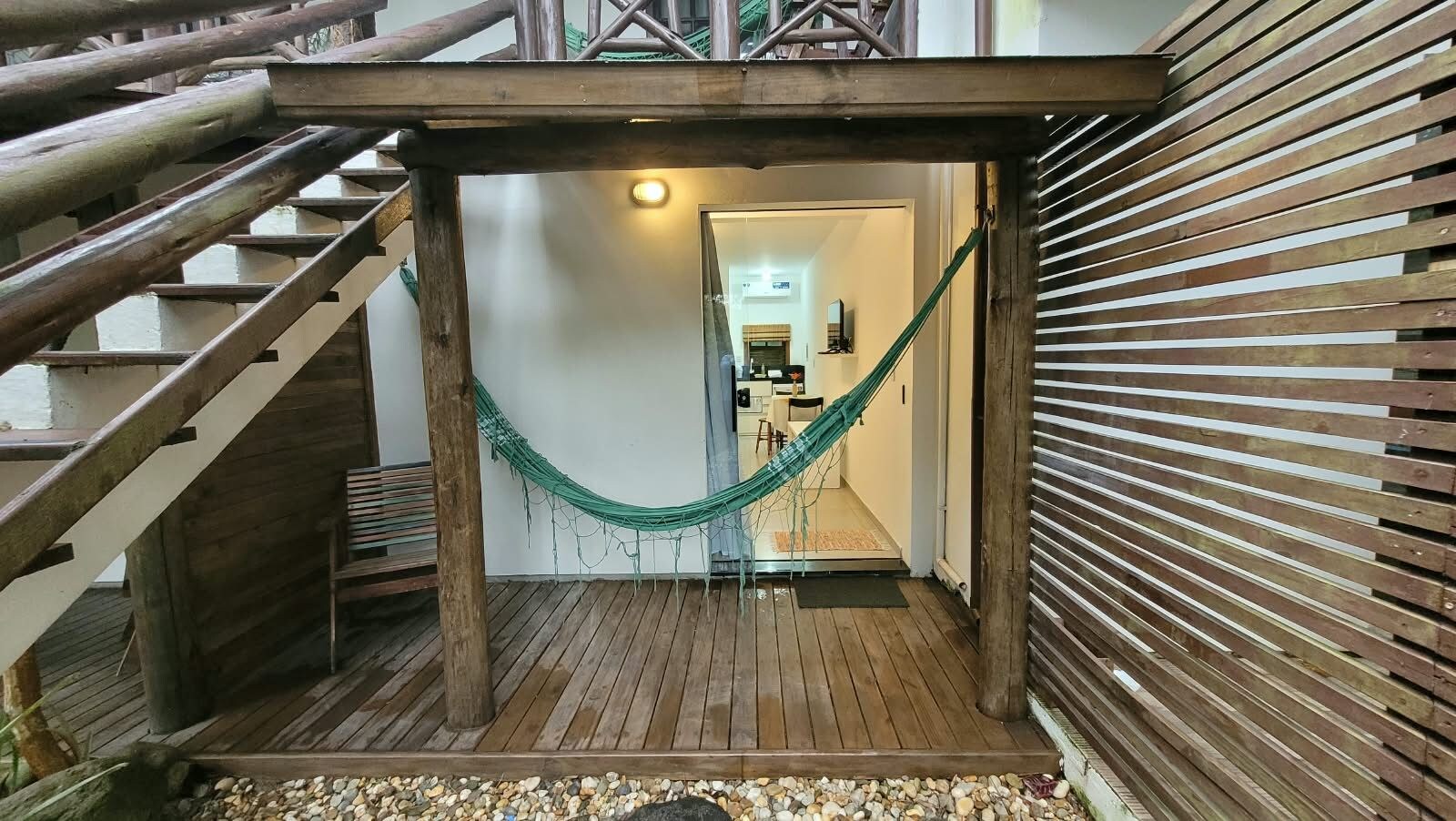Una escala de fusta que porta a una habitació amb una cadira lligadora i vistes a una cuina.