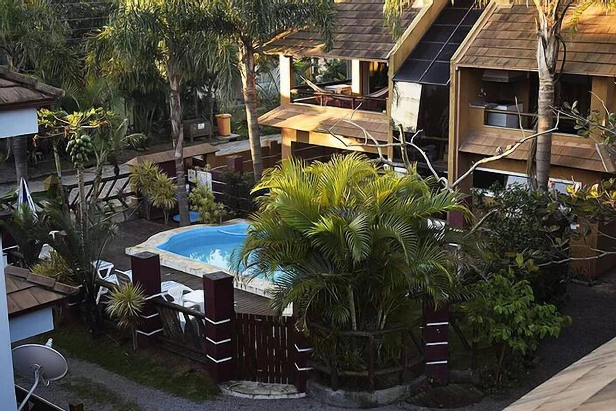 Ein Pool, umgeben von Palmen und einer Holzterrasse.