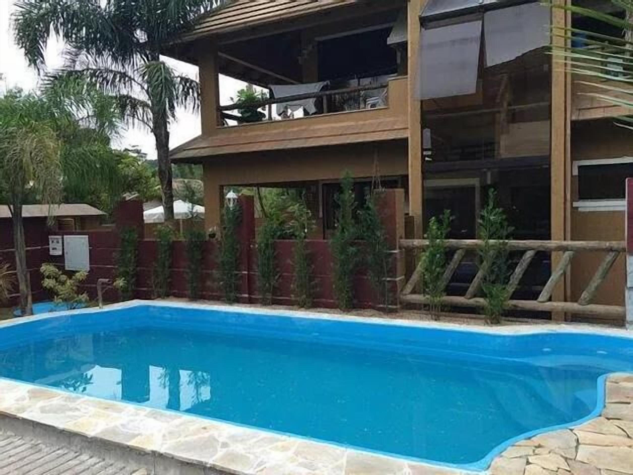 Um edifício de dois andares com uma piscina em frente.