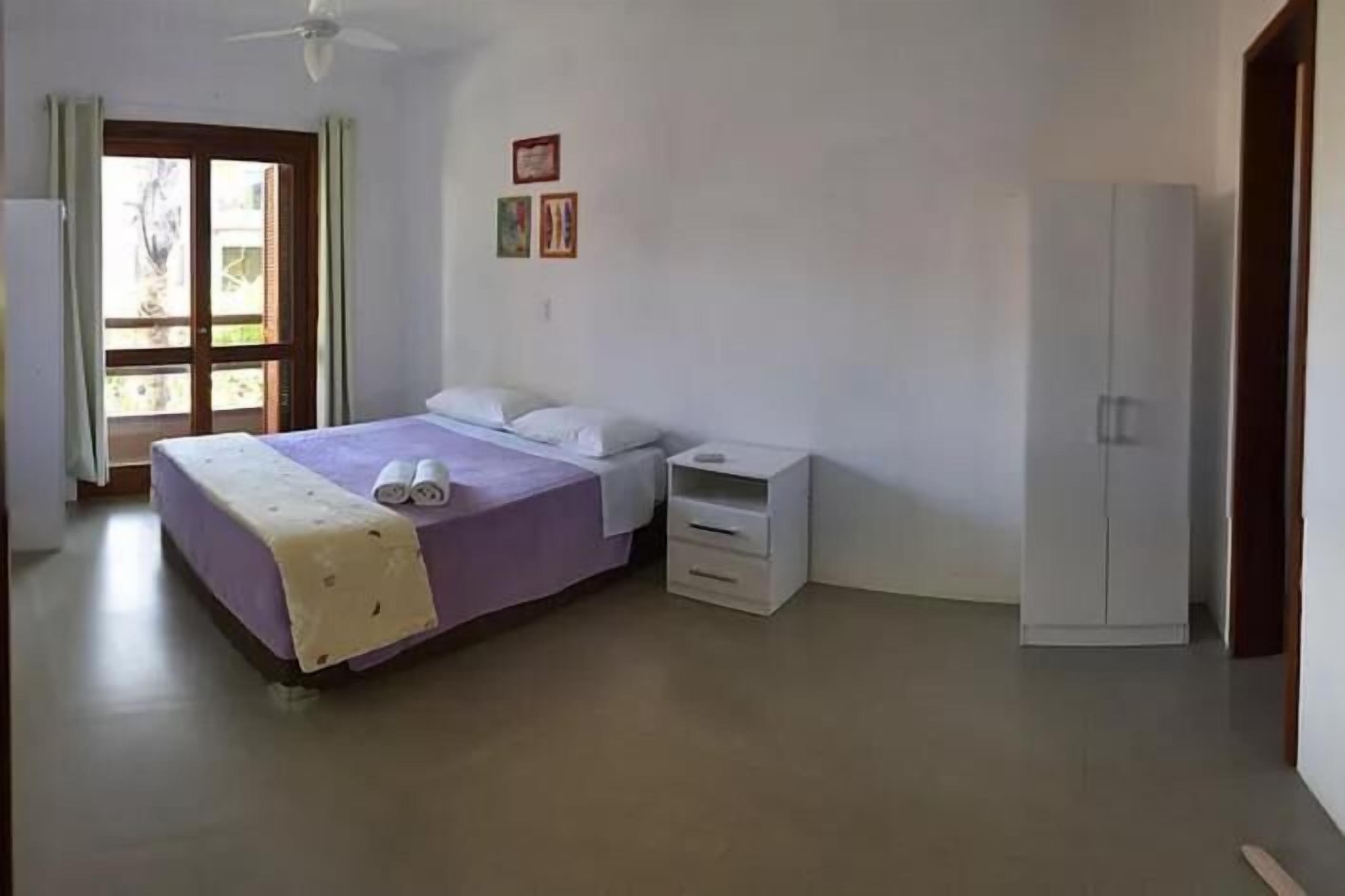 A bedroom with a bed, a nightstand, a wardrobe, and a window.