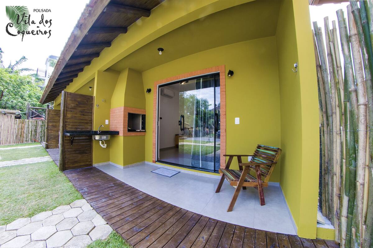 Eine Terrassenfläche mit Holzdeck, eine Glastür, die zu einem Innenbereich führt, und ein Sitzbereich mit einem Sessel.