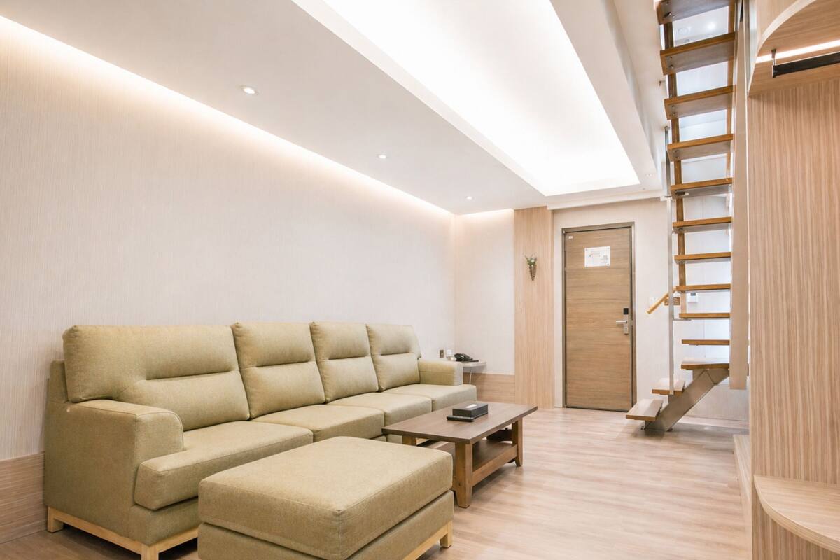A modern living room with a sofa, ottoman, and a wooden coffee table.