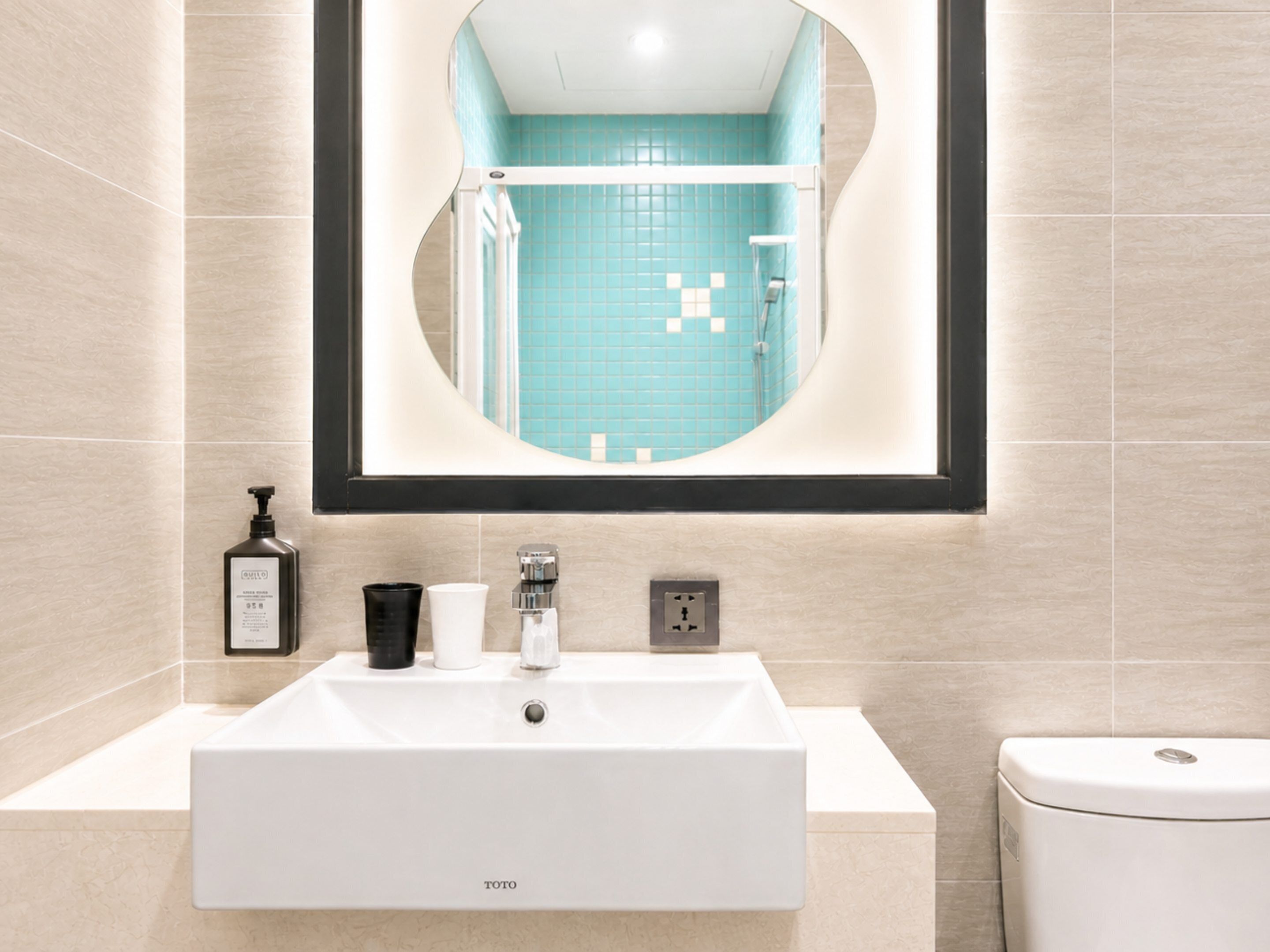 Un baño con lavamanos blanco, un espejo y un inodoro.
