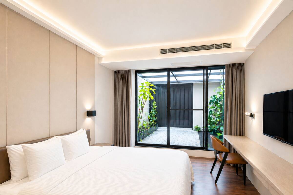 A modern hotel room with a large bed, a desk, and a TV.