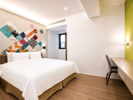 Una habitación de hotel moderna con una cama grande, un escritorio y una obra de arte geométrica y colorida en la pared.