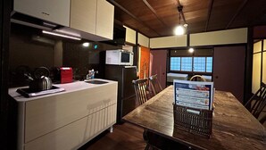 A modern kitchen with a wooden dining table, a microwave, and a kettle. - Kamiza-an Kamanza-tei (Kyoto)