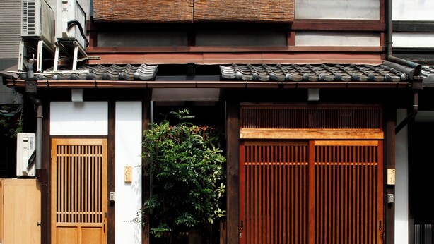 A traditional Japanese building with a wooden gate, a tiled roof, and a small garden area. - Kamiza-an Kamanza-tei (Kyoto)