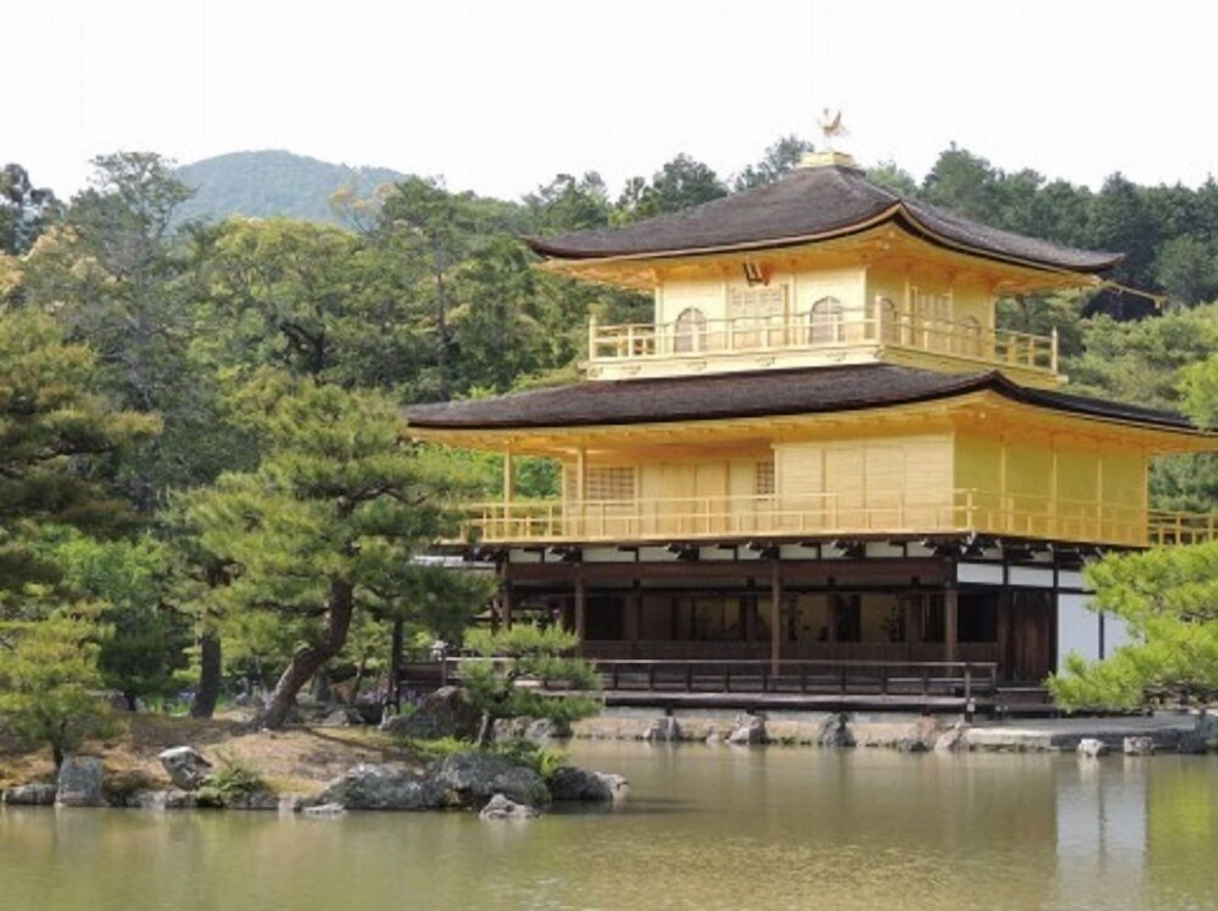 A traditional Japanese building with a two-tiered roof, surrounded by a tranquil pond and lush greenery.
