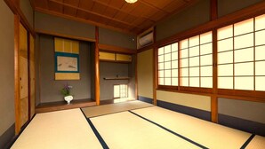 Een traditionele Japanse kamer met tatami vloeren, schuifdeuren en een hanglamp.