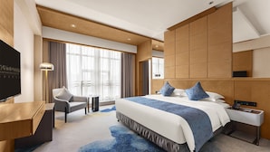Une chambre d’hôtel moderne équipée d’un grand lit, d’un bureau, d’une chaise et d’un téléviseur.