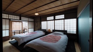 A traditional Japanese room with tatami flooring, two beds with pink bedding, a sliding door, and a view of the outside. - Shofu-an Kiyomizu-tei (Kyoto)