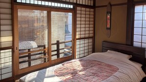 A traditional Japanese room with tatami flooring, a sliding shoji screen door, and a bed with a floral-patterned quilt. - Shofu-an Kiyomizu-tei (Kyoto)