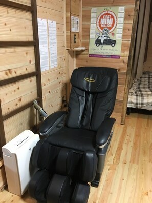 Ein Massagesessel in einem Holzraum mit einem Poster an der Wand.