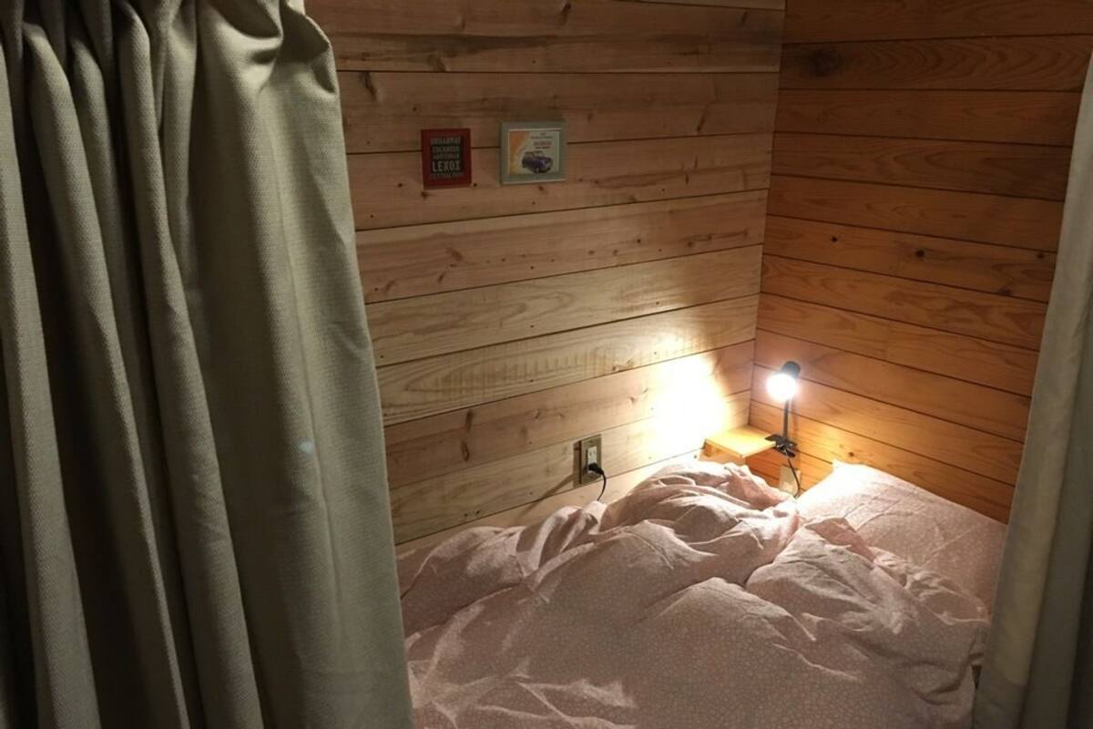A cozy cabin room with a bed, a nightstand with a lamp, and wooden walls.