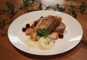 A plate with a dessert consisting of bread, berries, and a dollop of cream.