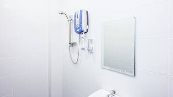 A bathroom with a shower, a hand dryer, and a mirror.