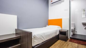 Een moderne hotelkamer met een eenpersoonsbed, houten nachtkastjes, een witte muur, een oranje accentmuur, een wit plafond en een houten vloer.