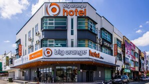 Um edifício de hotel moderno com uma placa chamativa 'big orange hotel'.