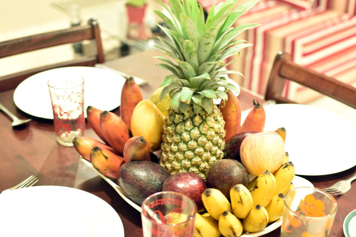 A dining table with a fruit platter, glasses, and plates.