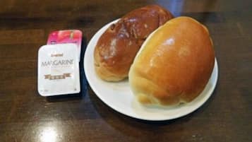 Une assiette avec deux petits pains et un paquet de margarine.