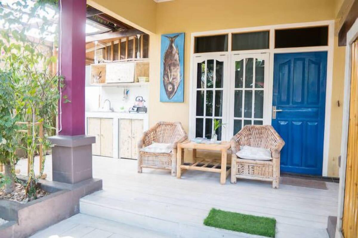 A porch with wicker furniture, a blue door, and a fish painting.
