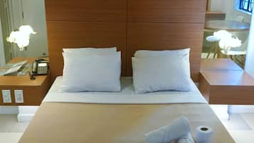A hotel room with a large bed, two pillows, a bedside table with a phone, and a window with a view.