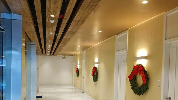 Un pasillo de hotel con suelo de mármol, vigas de madera en el techo y paredes decoradas con guirnaldas.