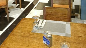 Un restaurante con mesas y sillas de madera, suelo a cuadros, iluminación colgante y una pantalla de televisión en la pared.