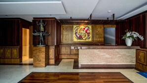 A reception area with a wooden reception desk, a statue, and a colorful abstract painting on the wall.