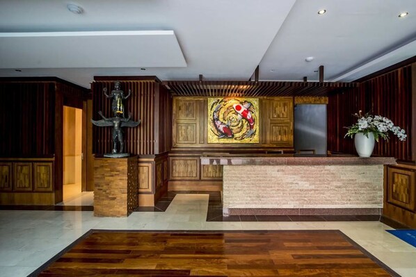 A reception area with a wooden reception desk, a statue, and a colorful abstract painting on the wall.