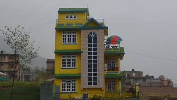 Un edificio amarillo de varios pisos con una torre central, un gran ventanal arqueado y un paraguas de colores en el techo.