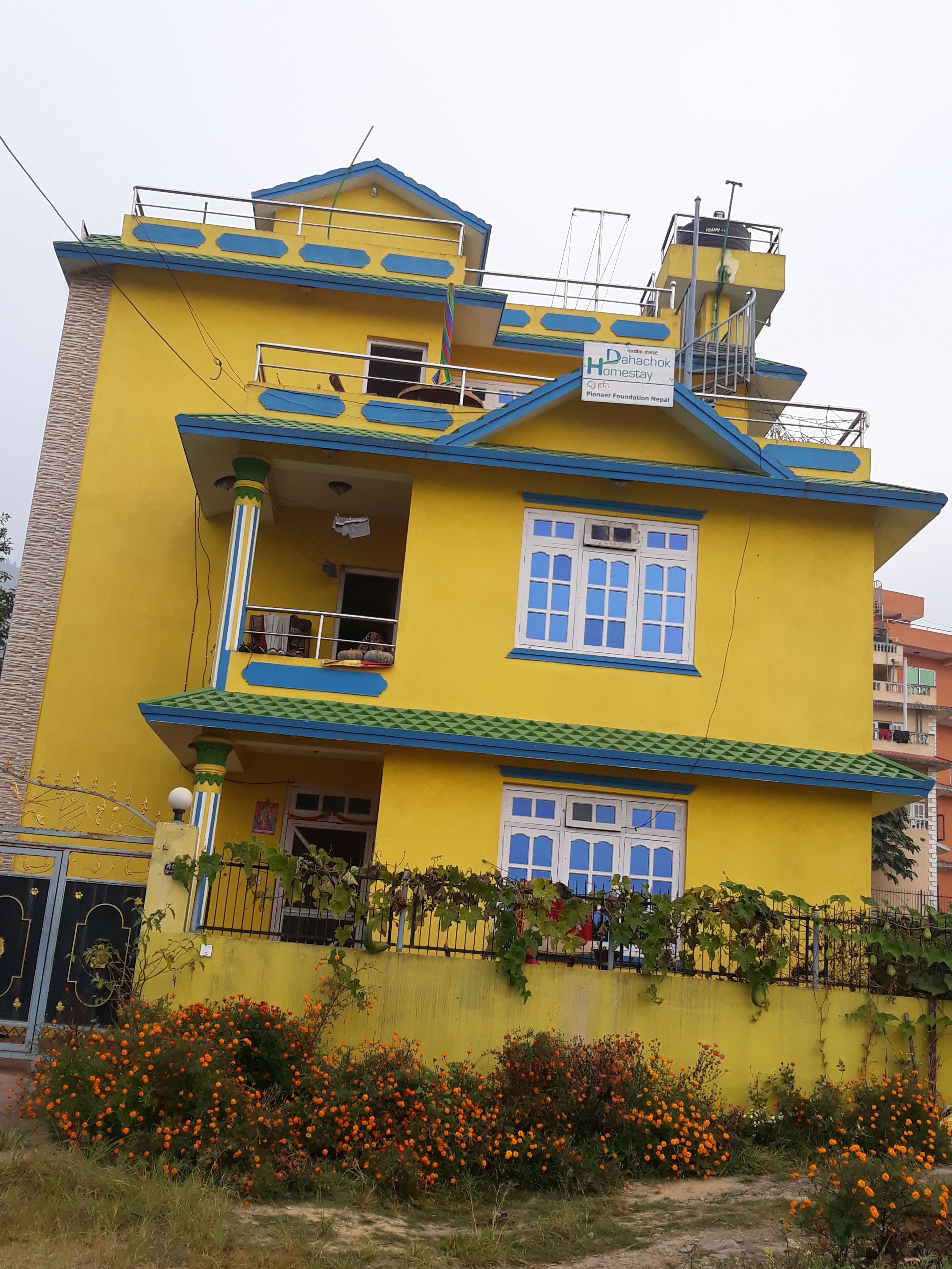 A multi-story yellow building with a sign indicating it is a Pioneer Foundation Nepal hotel.