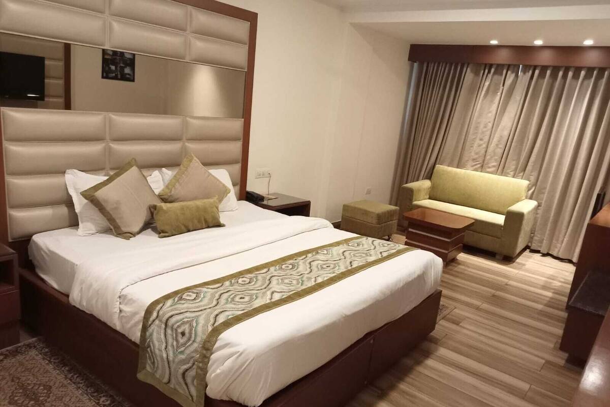 A hotel room with a large bed, a sofa, a small table, and a television.