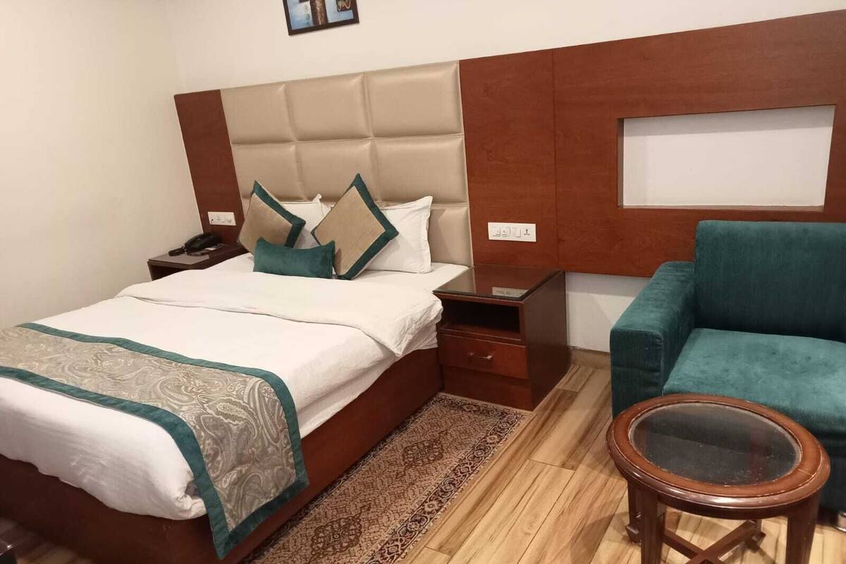 A hotel room with a bed, a nightstand, a chair, and a small table.