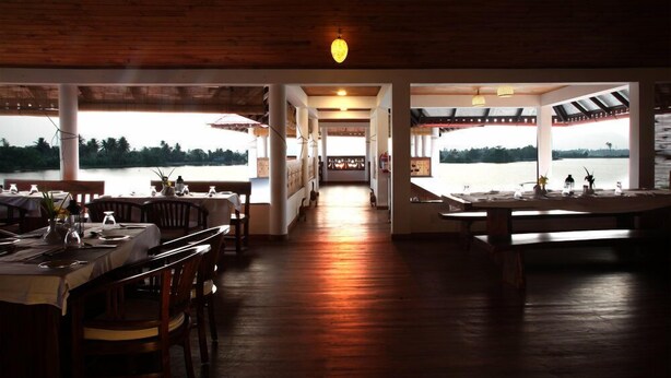 Un restaurant à l’intérieur en bois, doté de grandes fenêtres et offrant une vue sur l’eau.