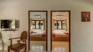 A room with a wooden chair, a bed with a red and white checkered bedspread, a television on the wall, and a painting on the wall. - Samui Green Space Resort (Koh Samui)