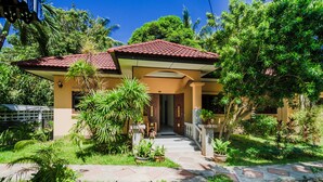 A house with a red-tiled roof, a covered porch, and a garden with various plants and a pathway leading to the entrance. - Samui Green Space Resort (Koh Samui)