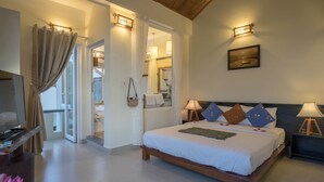Un dormitorio con cama, lámparas de noche, televisor y vistas al exterior.
